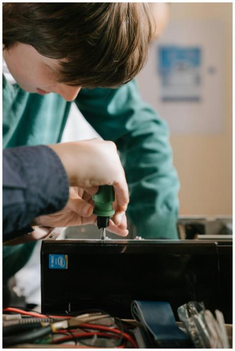 Close-up of hands repairing a computer with a scre