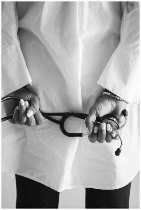 Black and white image of a doctor holding a stetho