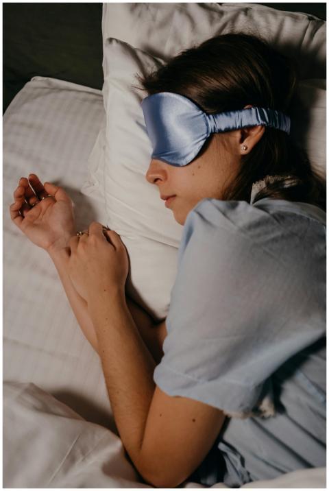 A woman wearing a blue eye mask rests peacefully i