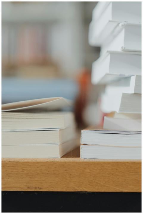 Close-up of stacked white books on a wooden table