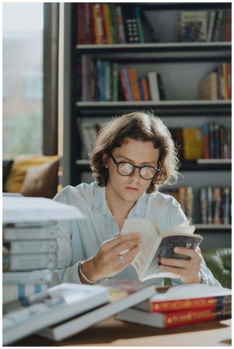 A young man reading a book in a cozy bookstore, su