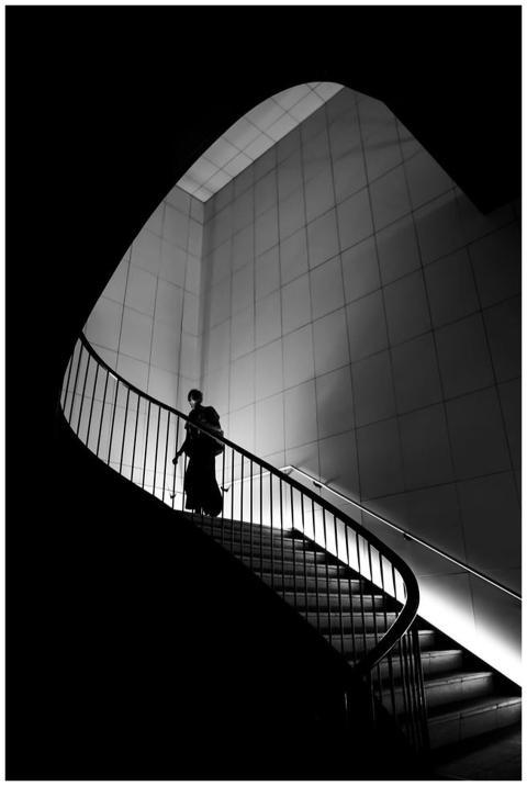 A silhouette of a person ascending a modern, curve