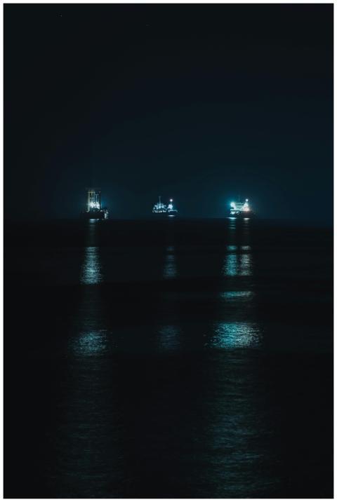 A serene night view of illuminated ships on the oc
