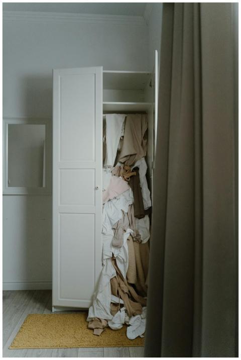 A cluttered wardrobe overflowing with various clot