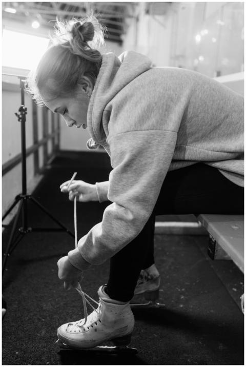 A woman tying her ice skates, preparing for figure
