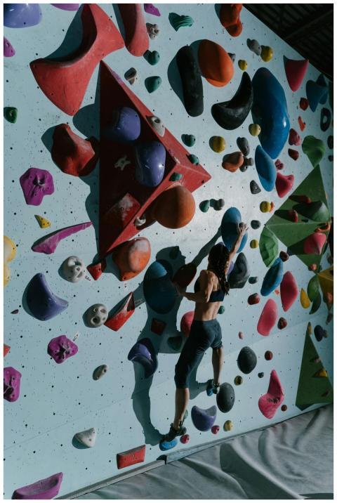 Female athlete bouldering on an indoor climbing wa