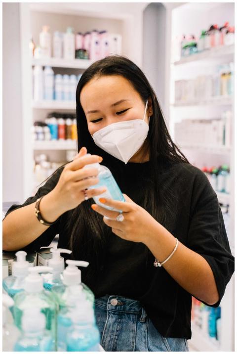 Woman wearing a mask selects hand sanitizer in a s