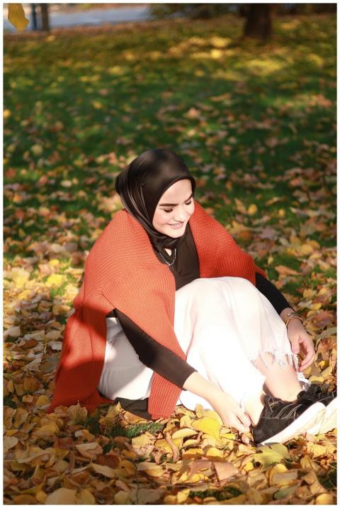 Young woman sitting in autumn leaves wearing an or