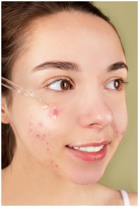 Close-up of a young woman applying serum on her fa
