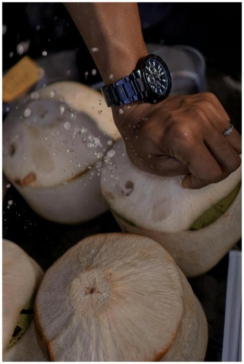 Hand opening a fresh coconut, capturing water drop