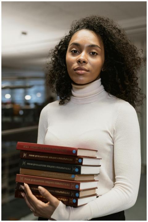 Young woman with curly hair holding books, emphasi
