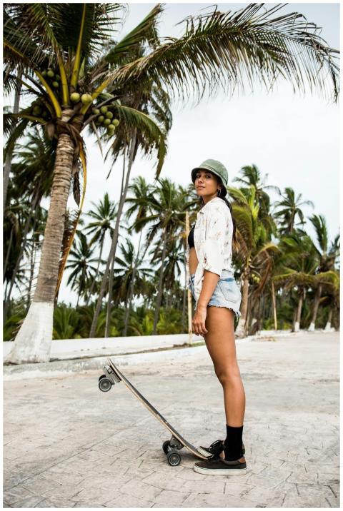 Young woman with longboard in tropical setting loo