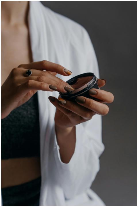 Close-up image of a woman holding a cosmetic conta