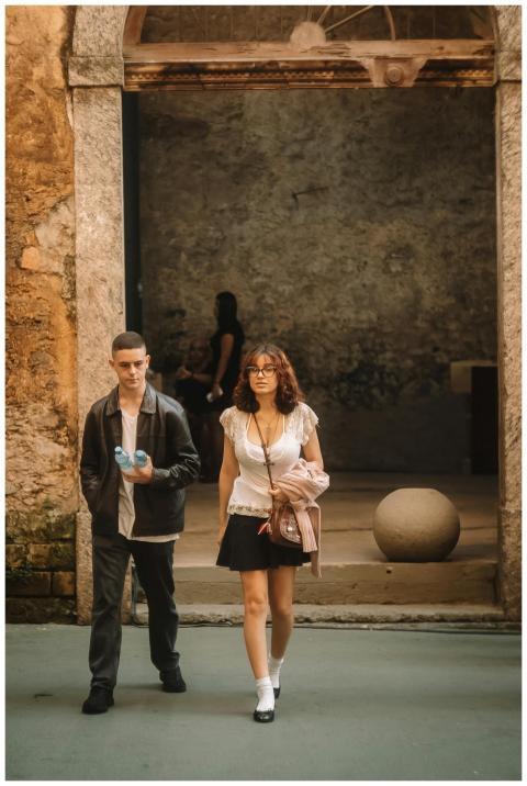 Two young adults walk through an ancient stone arc