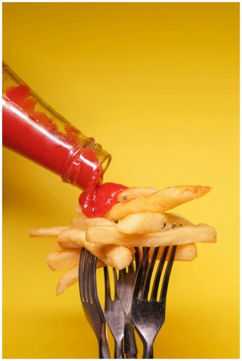 Forks with fried potatoes and bottle with ketchup