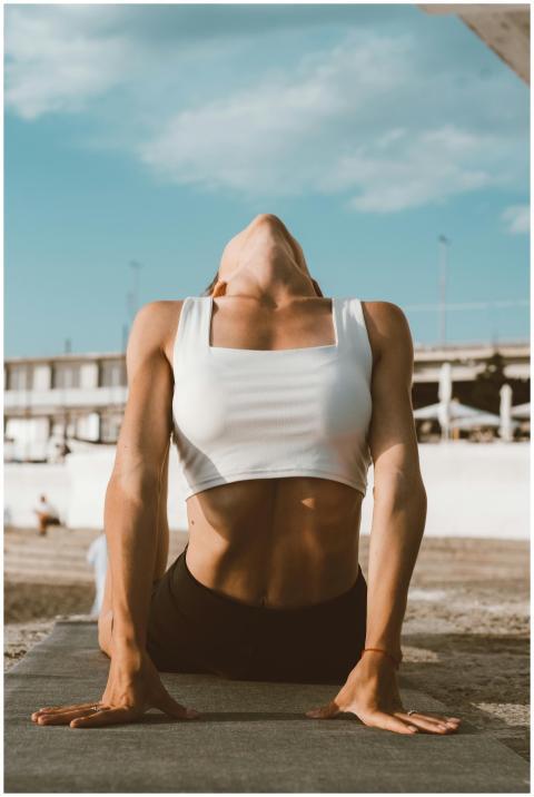 A woman in a white crop top performing yoga stretc