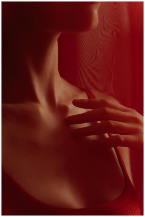 Close-up of a person touching their chest with han