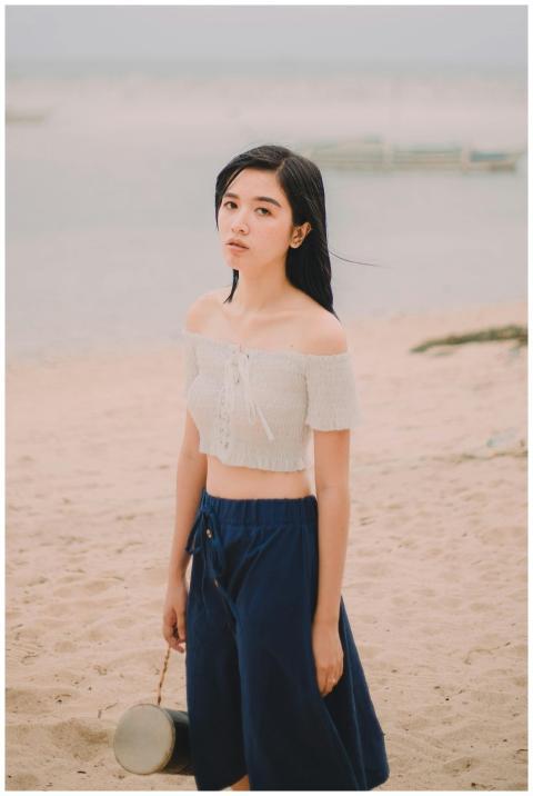 Asian woman in a crop top on a sandy beach in the