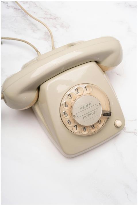 A classic beige rotary telephone on a white marble