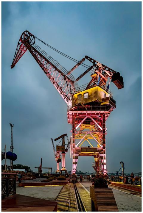 A brightly lit industrial crane against a dramatic