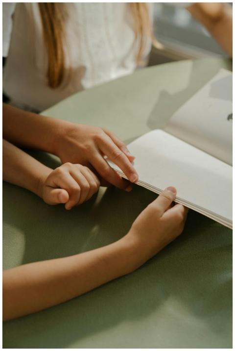 Hands of children turning pages of a book in warm