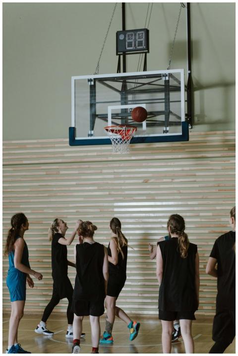 A team of young women playing basketball indoors,