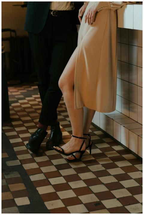 An elegant couple stands at a tiled bar counter, s