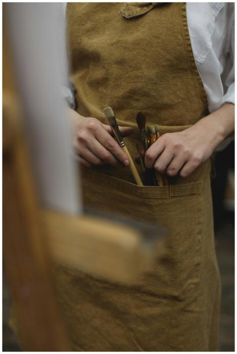 Artist in apron organizing paint brushes in an ind