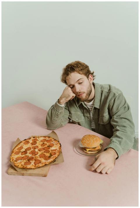 A young man rests his head on his hand, sitting wi