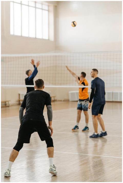 Four men engaged in an indoor volleyball game, sho