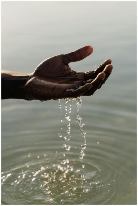 A close-up of a hand with water droplets falling o