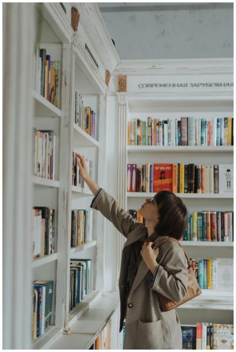 A young woman reaching for a book on a stylish lib