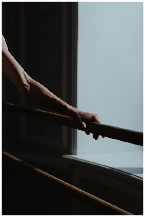 Close-up of a hand resting on a ballet barre, capt