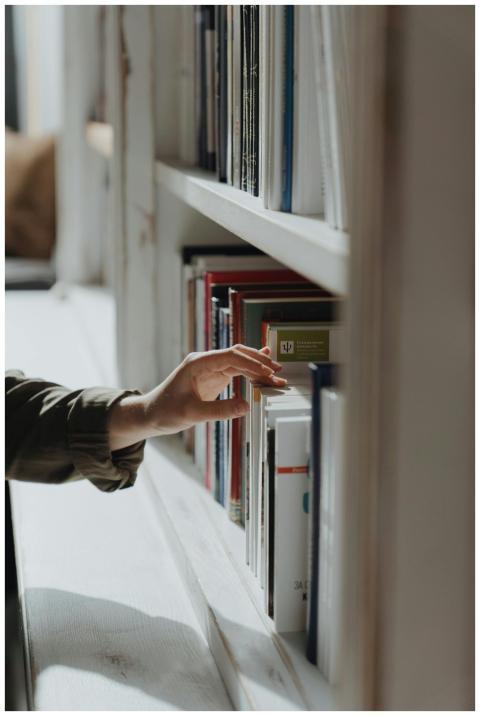 A hand reaches out to select a book from a well-ar