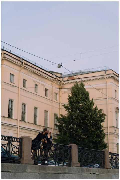 A couple embraces on a city balcony near a histori