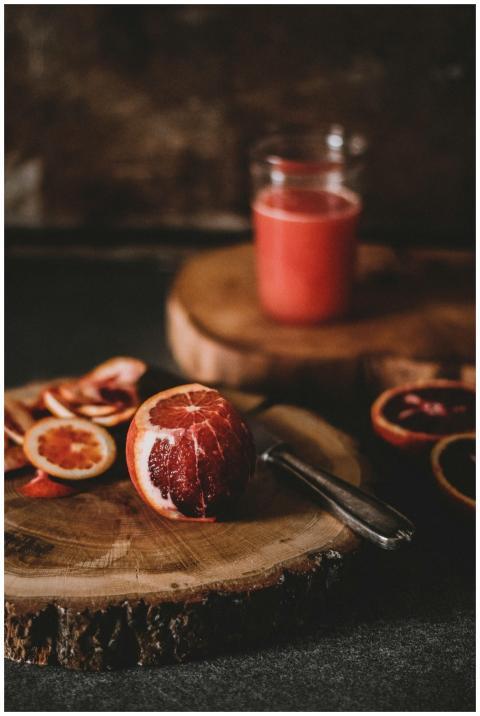 Blood orange juice and sliced citrus on a rustic w