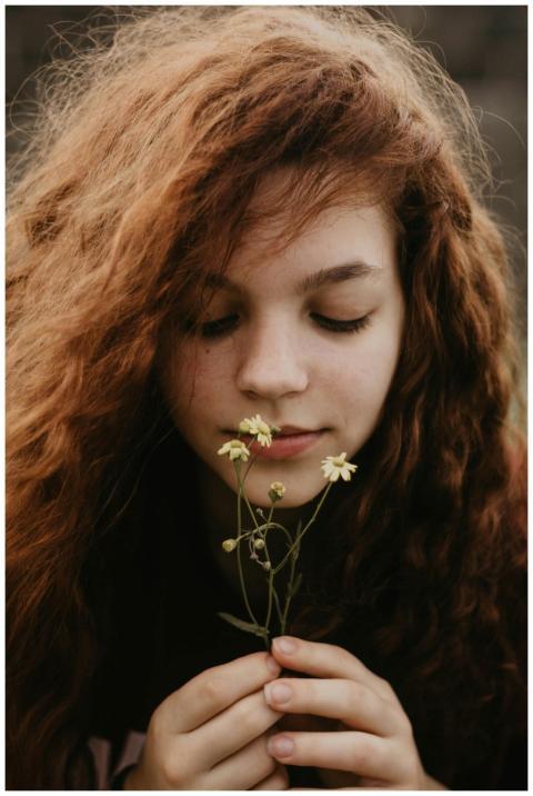 Teenage girl with long red hair holding small whit