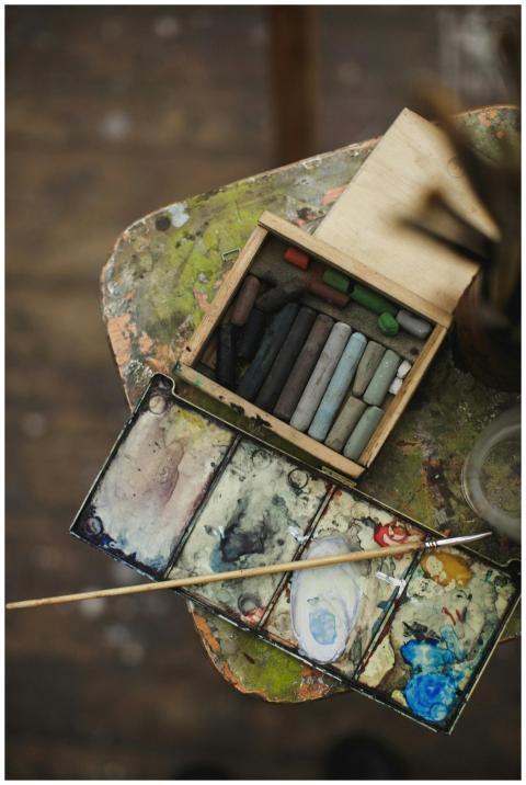 A close-up of used watercolor palette and pastel s