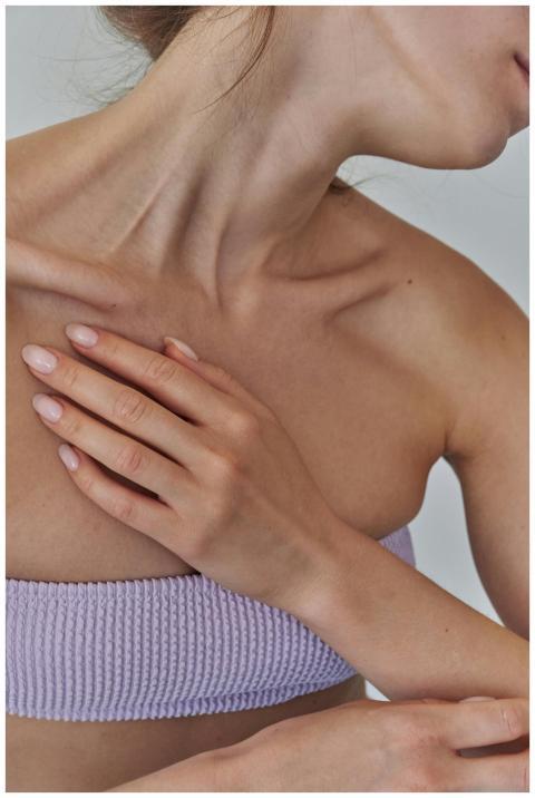 Close-up of a woman's hand resting on her collarbo