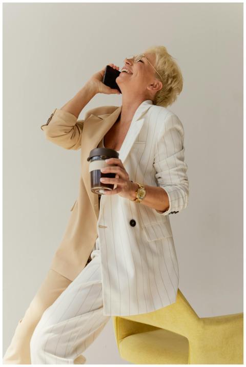 Cheerful woman in a suit enjoying a phone call whi