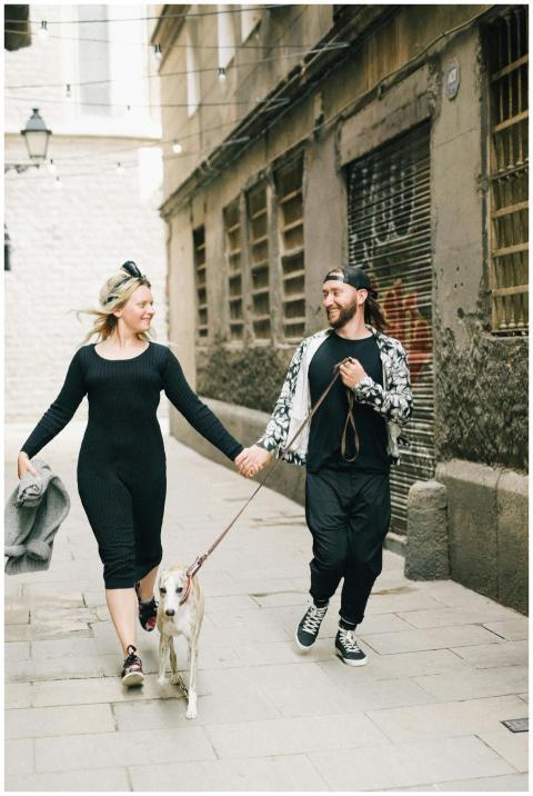 A cheerful couple walking their dog down a charmin