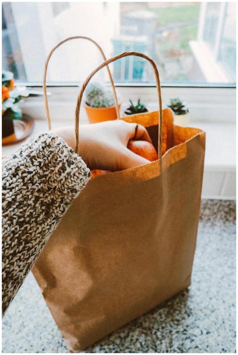 Close-up of a hand taking groceries from a paper b