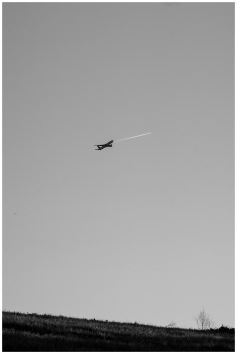 Black and white image of airplane flying over land