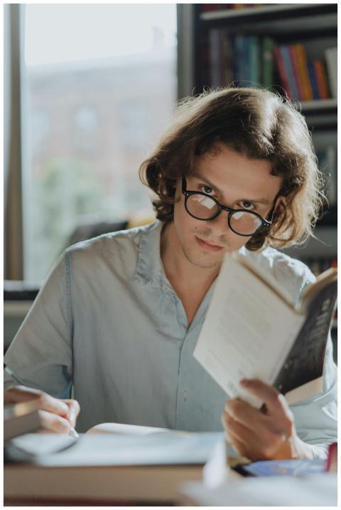 A young man with glasses reading and taking notes