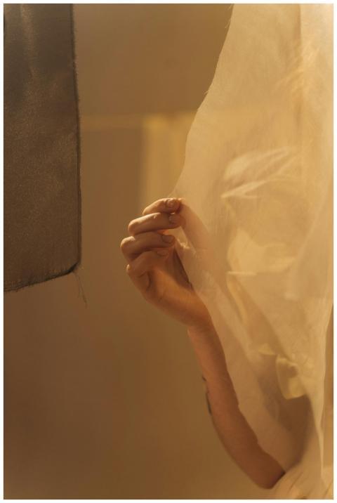 A hand gently holding a sheer fabric, creating a s