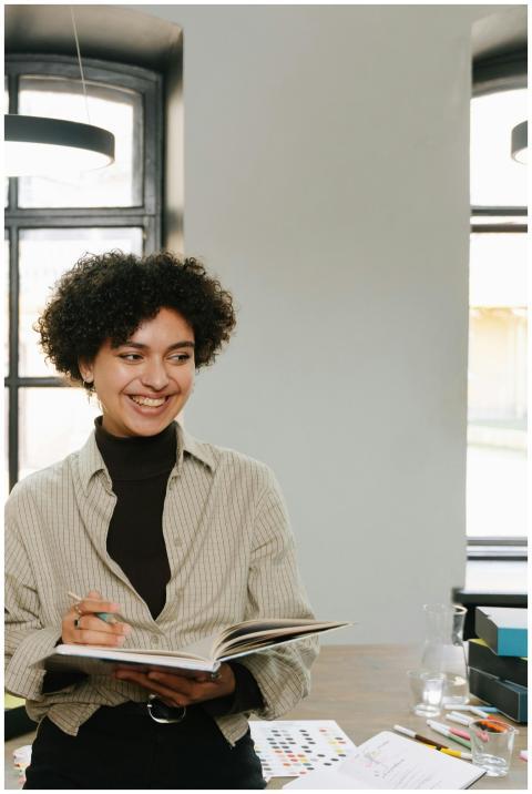 Smiling young woman holding a notebook in a modern
