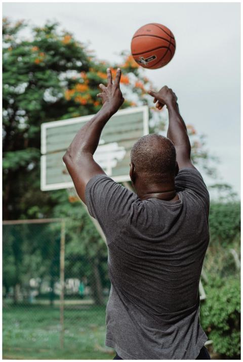 Adult man shooting a basketball on an outdoor cour