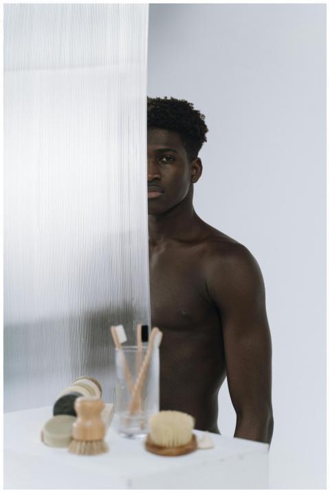 Artistic image of a shirtless man behind glass, wi