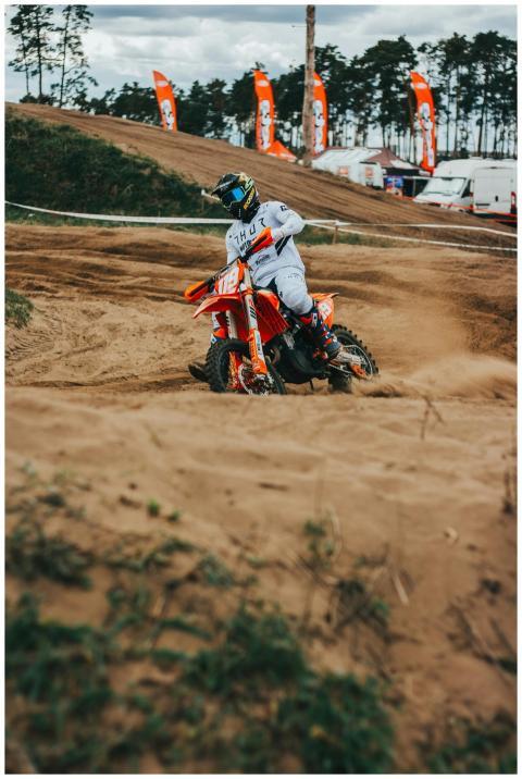 Motocross rider skillfully maneuvers a dirt track,