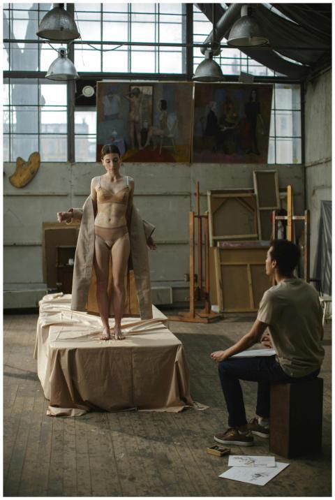 Nude female model posing in an artist's studio wit